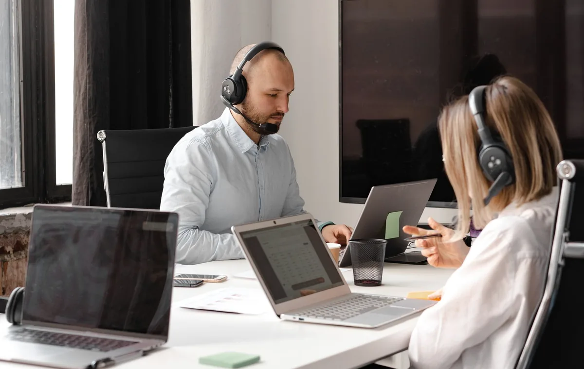 Customer support agents working together with laptops and headsets