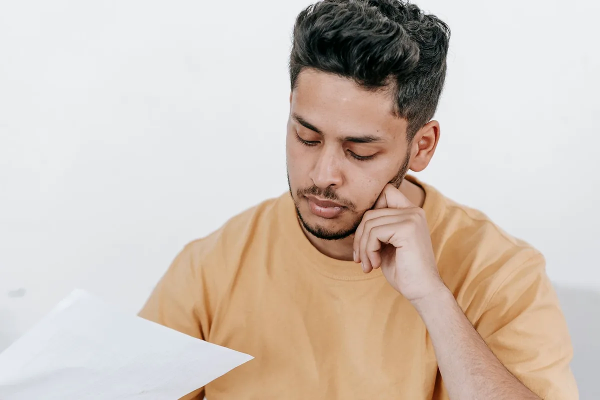 Person reviewing documents beside a laptop while preparing information